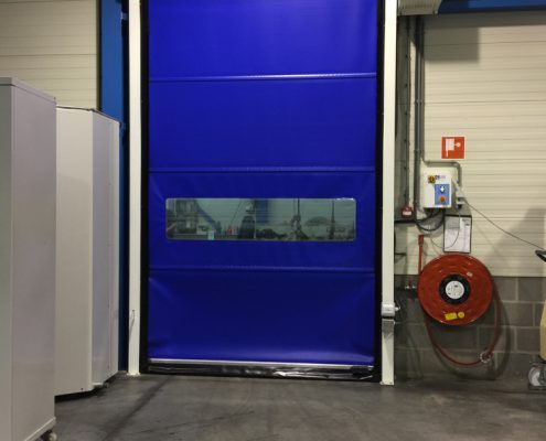 Niebieska brama przemysłowa rolowana WinRoll 150 w obiekcie magazynowym o małej powierzchni.