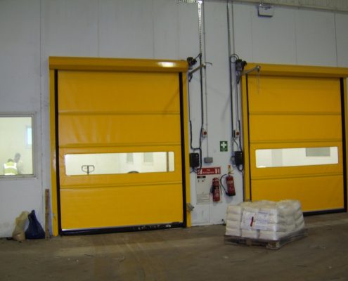 Żółte bramy przemysłowe, rolowane WinRoll 150 w obiekcie magazynowym.